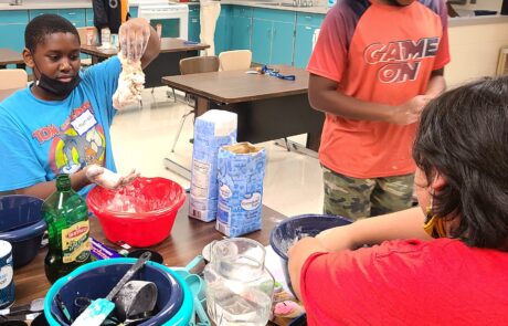 A middle school student is holding pizza dough during cooking activity.